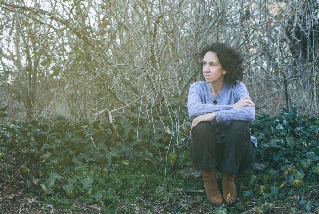 Fotografía de Ana Gil- Coach de Mindfulness y Astrología, sentada sobre césped